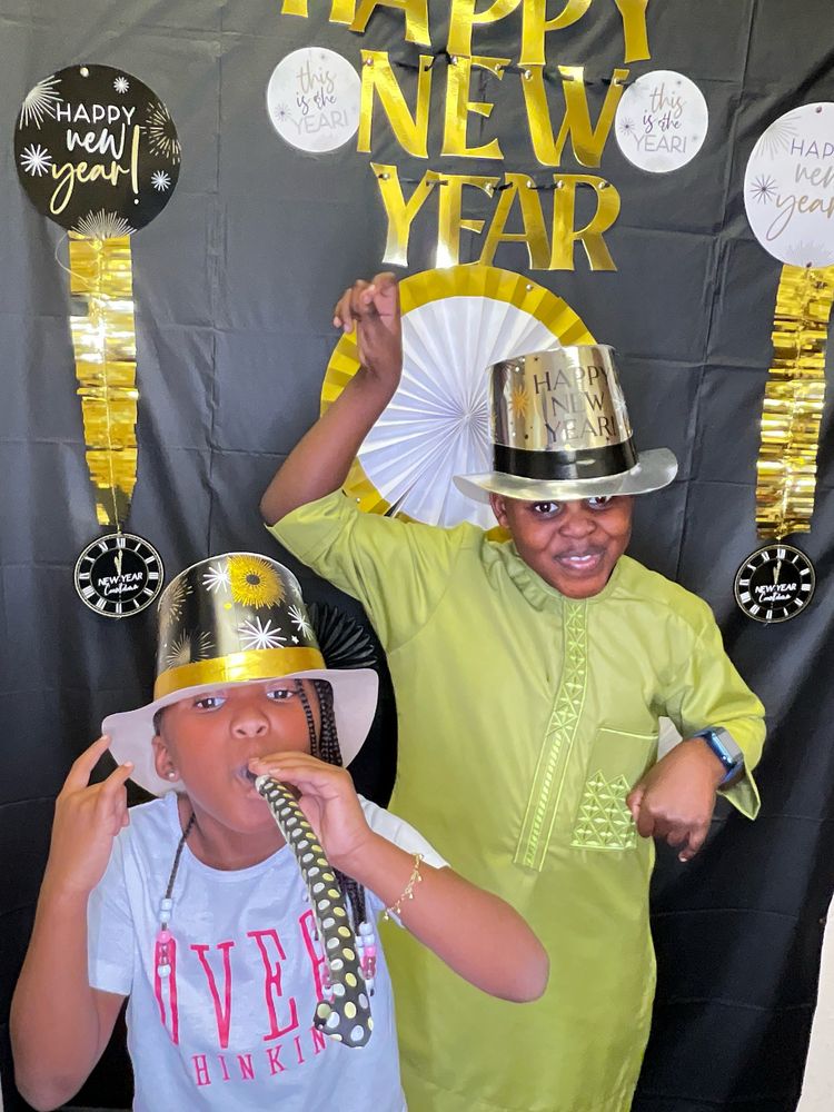 Kids in gold party hats celebrating at a New Year's Eve photo booth backdrop