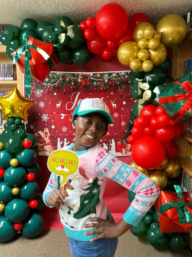 Young guest with a Ho Ho Ho prop sign at a holiday photo booth setup