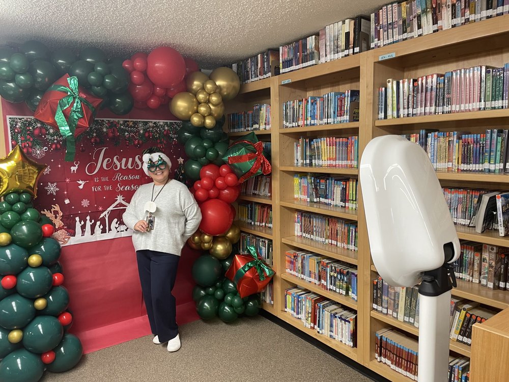 Guest posing with novelty glasses beside our photo booth at a holiday event